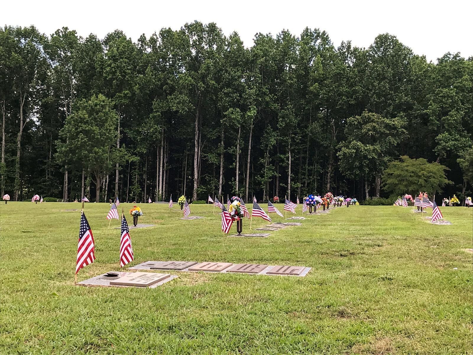 A cemetery with a lot of american flags in the grass.