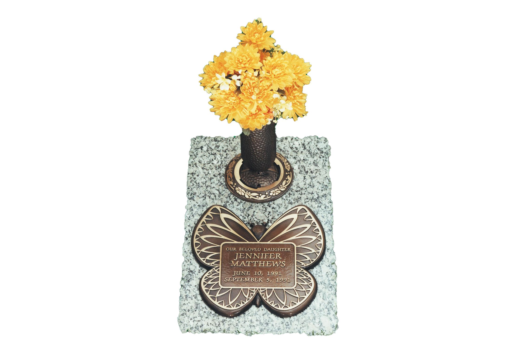 A vase of yellow flowers sits on top of a butterfly shaped grave marker.