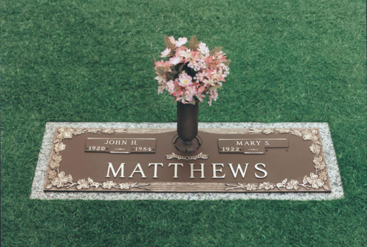 A gravestone for matthews with a vase of flowers on it