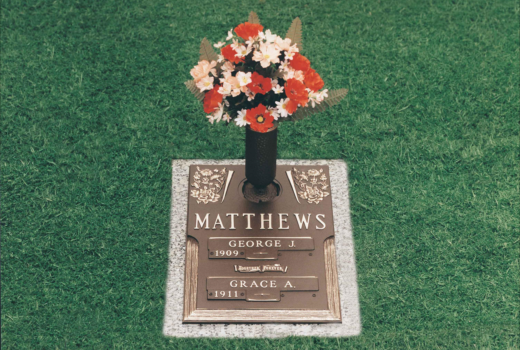 A gravestone for matthews with a vase of flowers on top