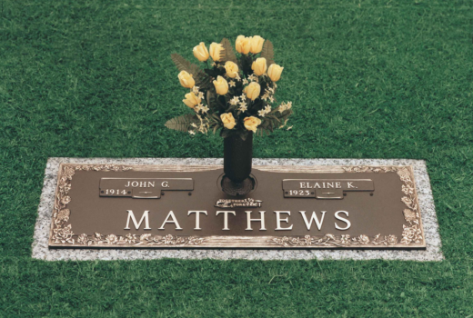 A grave of matthews with a vase of yellow roses