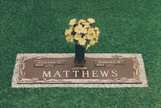 A gravestone for matthews with a vase of flowers on it