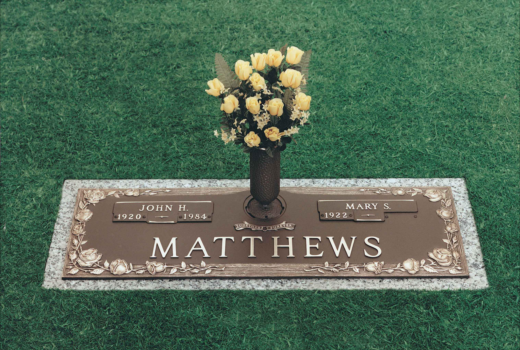 A grave marker for matthews with a vase of yellow roses