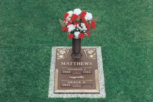 A grave with a vase of red and white flowers on it