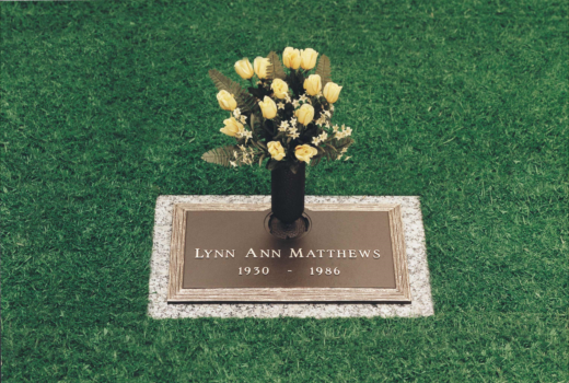A grave of lynn ann matthews with a vase of yellow roses