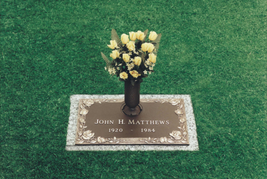 A gravestone for john h matthews with a vase of flowers on it.