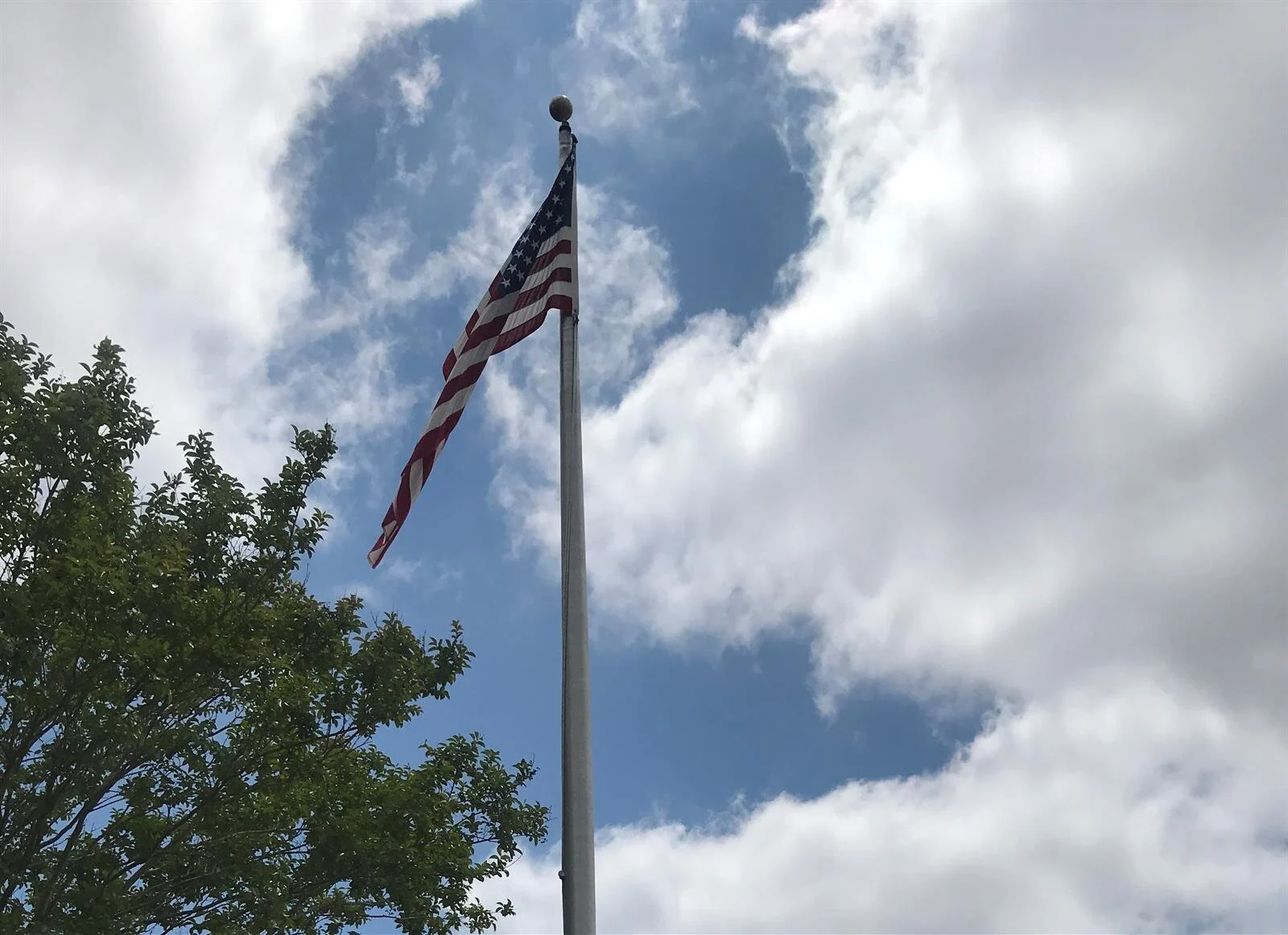 An american flag is flying in the wind against a cloudy blue sky