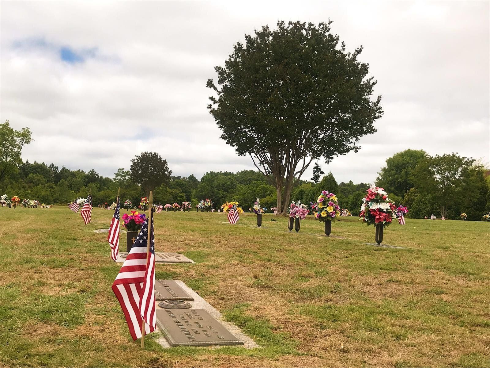 A cemetery with american flags and wreaths on graves