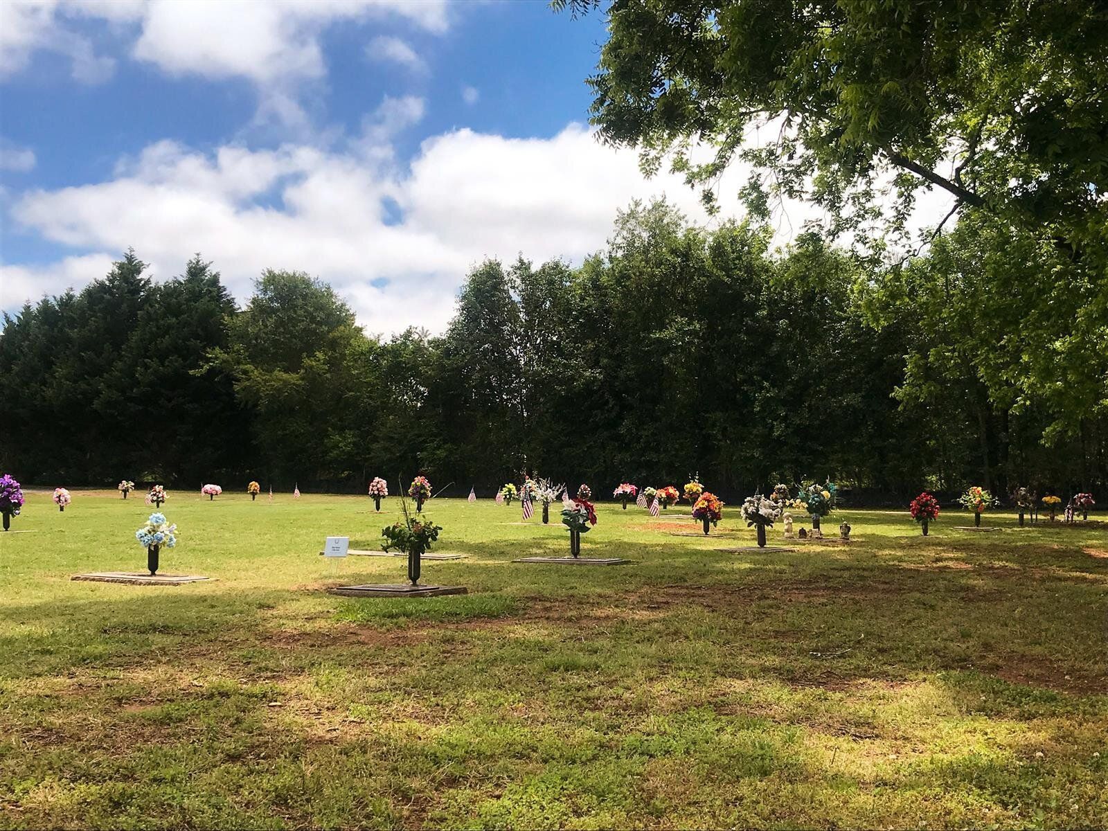 A cemetery filled with graves and flowers on a sunny day