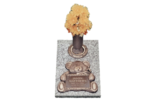 A grave with a teddy bear and a vase of flowers