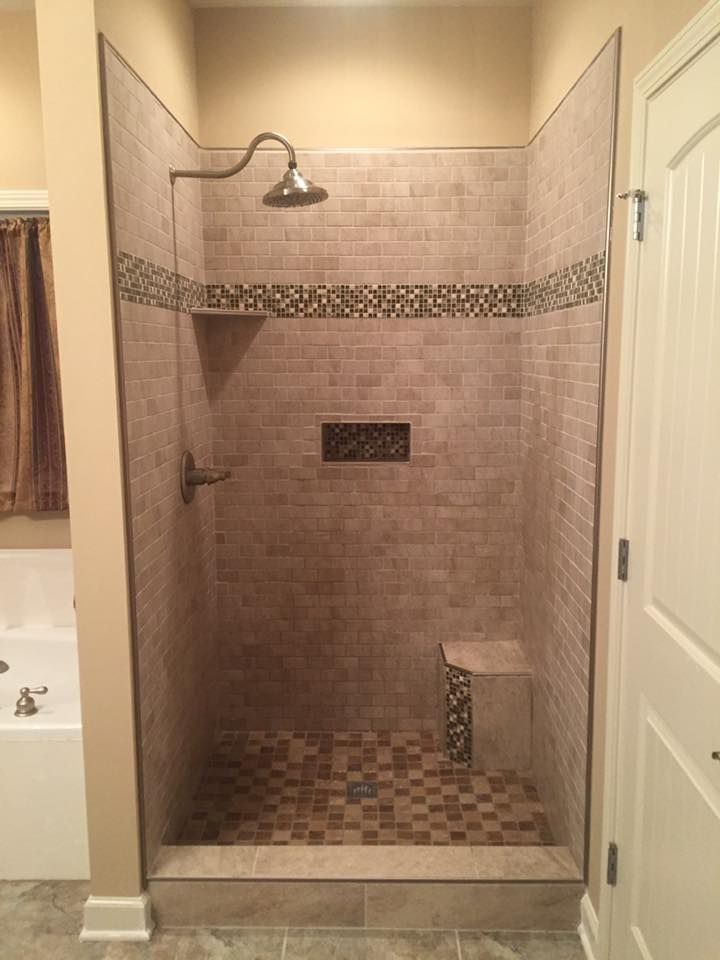 A bathroom with a walk in shower and a tub.