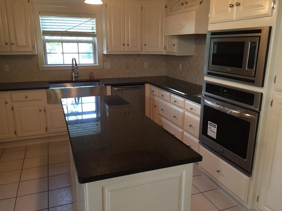 A kitchen with white cabinets and black counter tops