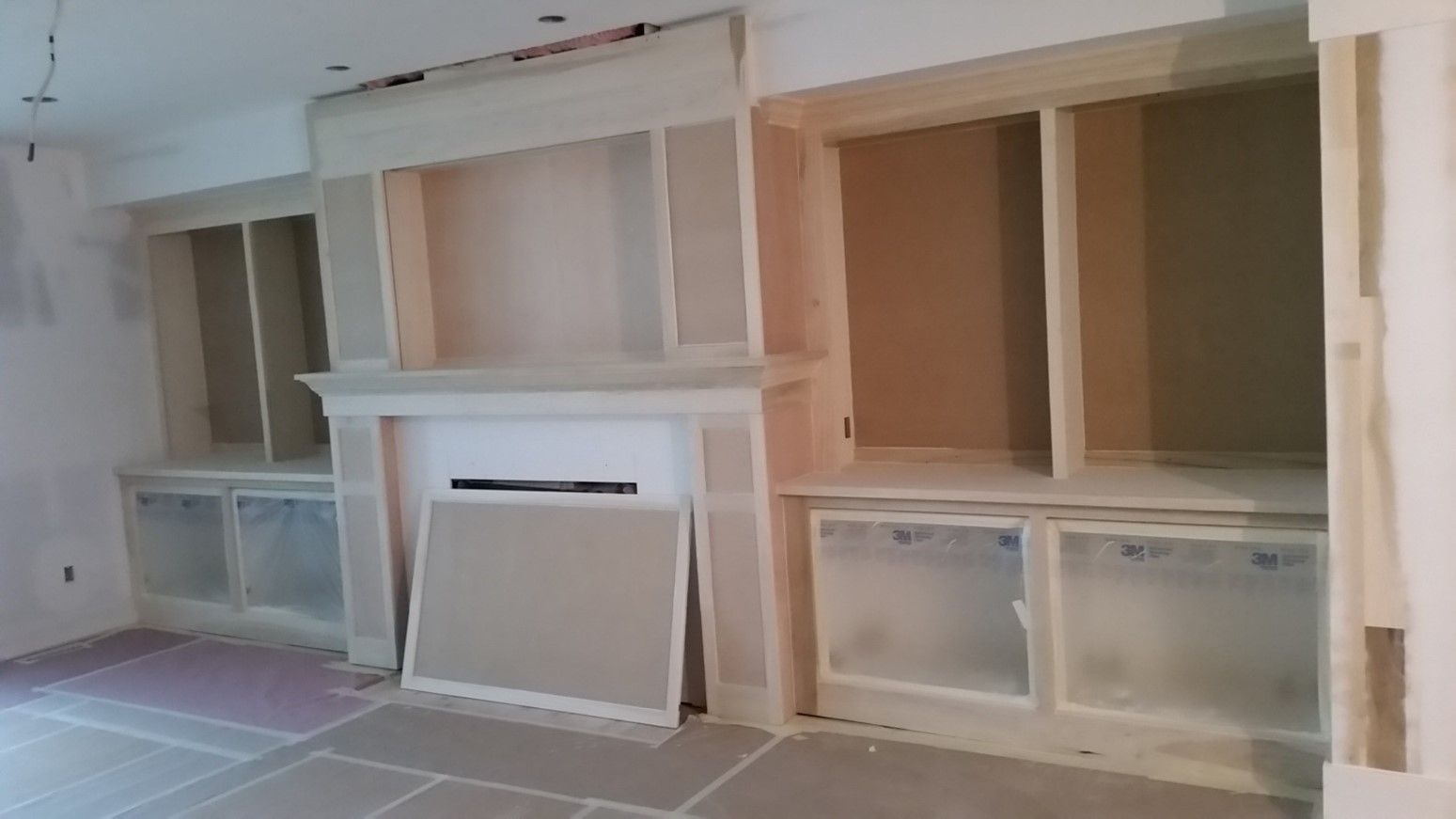 A living room with a fireplace and shelves under construction.