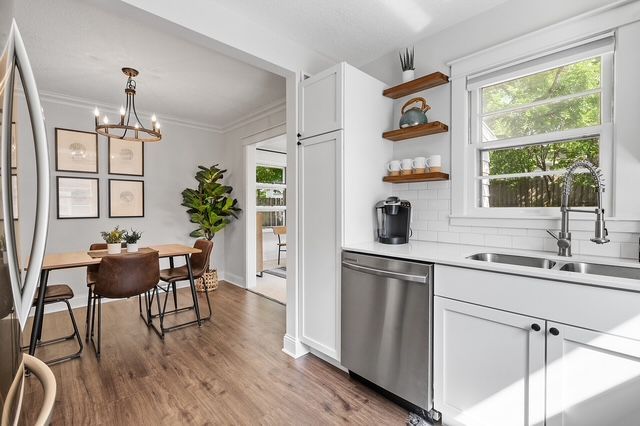 A kitchen with a sink , dishwasher , table and chairs.