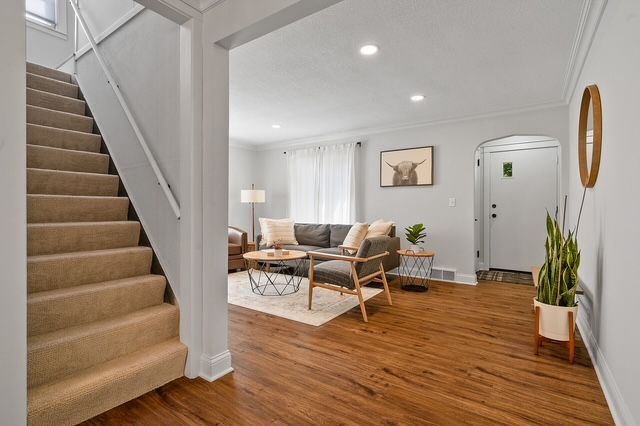 A living room with hardwood floors and stairs leading up to the second floor.