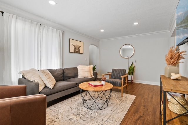 A living room with a couch , chairs , coffee table and television.
