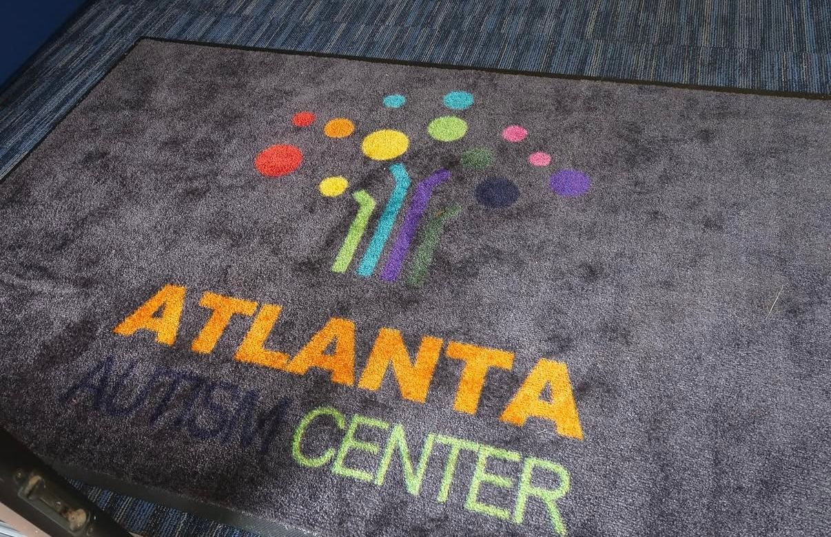 Doormat with "Atlanta Center" text and colorful logo, on a gray surface.
