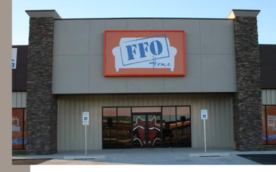The exterior of an FFO Home store featuring a prominent orange sign, a glass-door entrance, and two handicap parking signs.