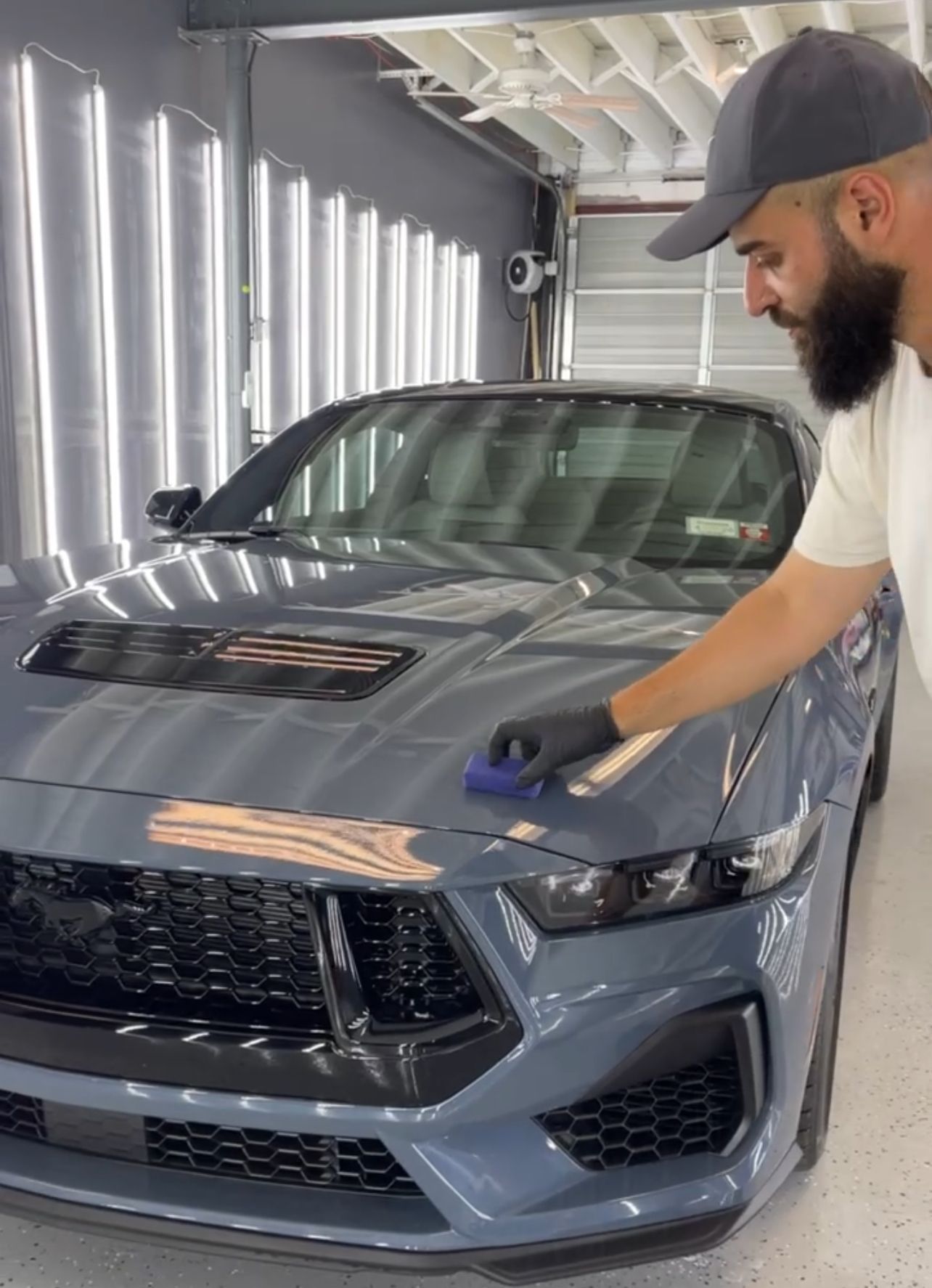 A person is cleaning the hood of a car with a cloth.