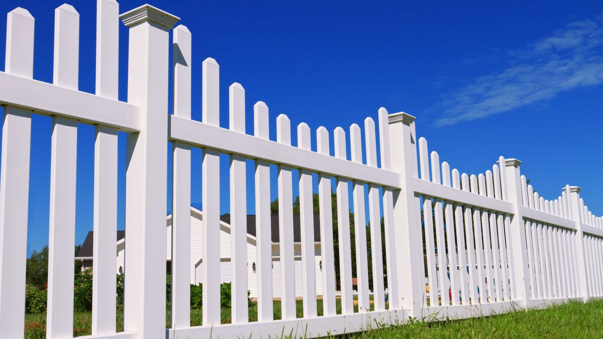 A white picket fence with a blue sky in the background