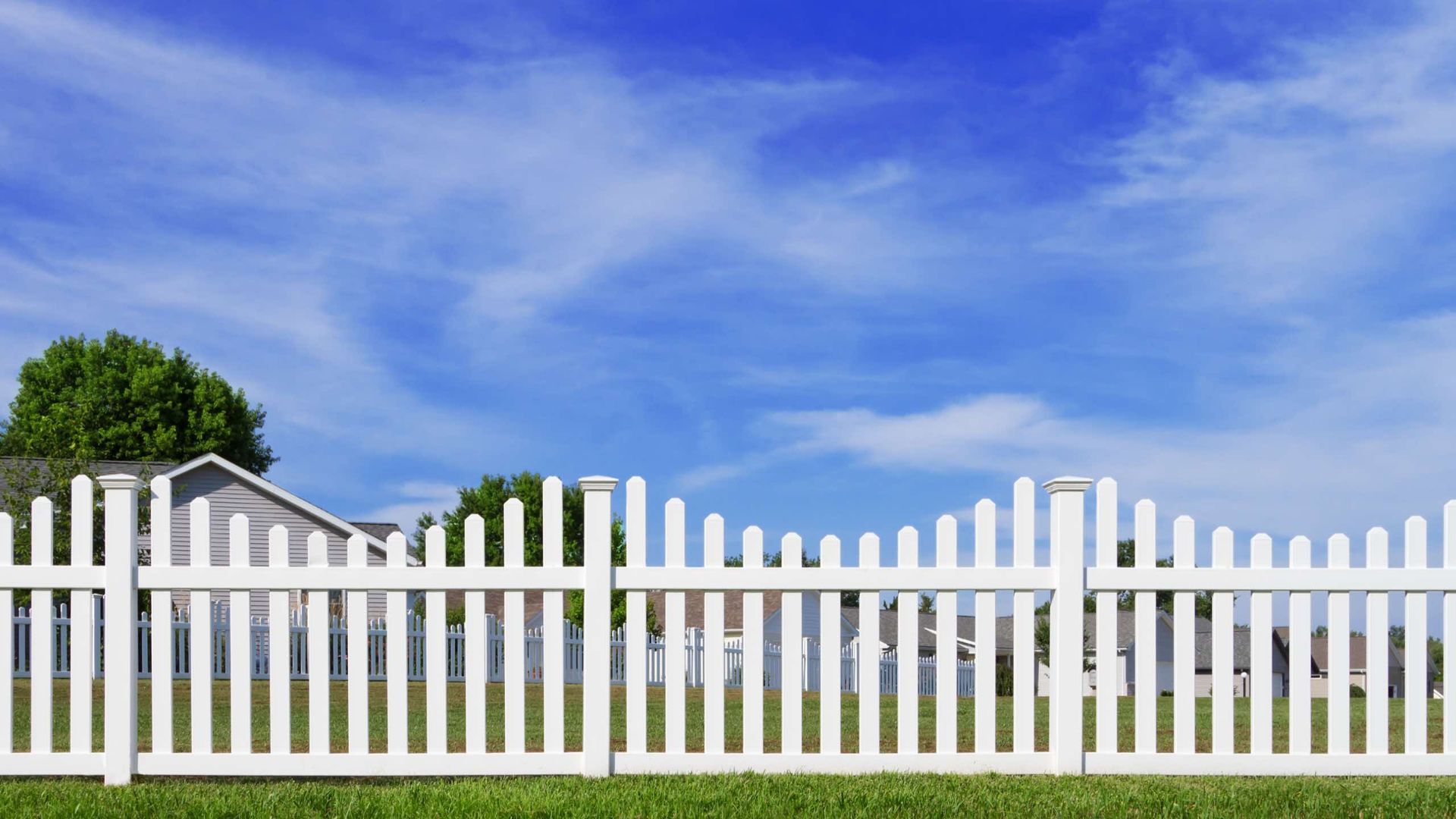 A white picket fence with a house in the background