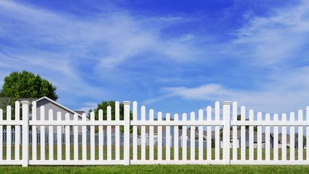 A white picket fence with a house in the background