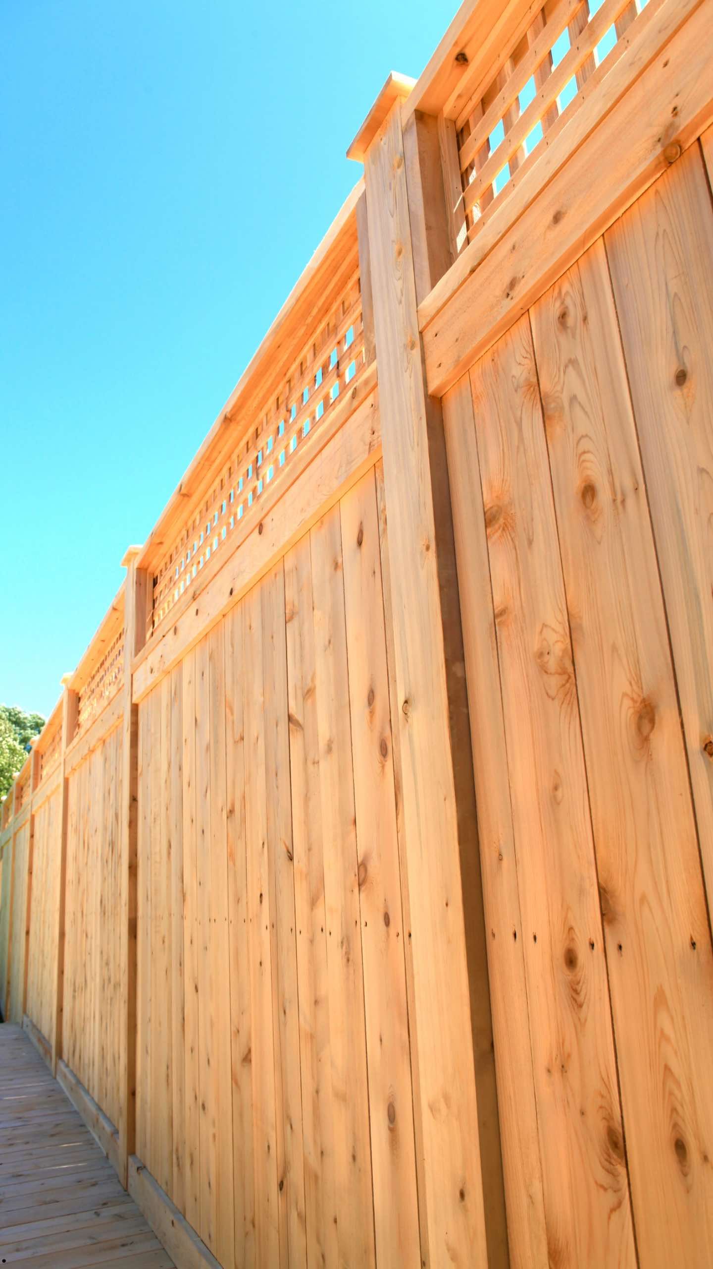 A wooden fence with a lattice top and a blue sky in the background.