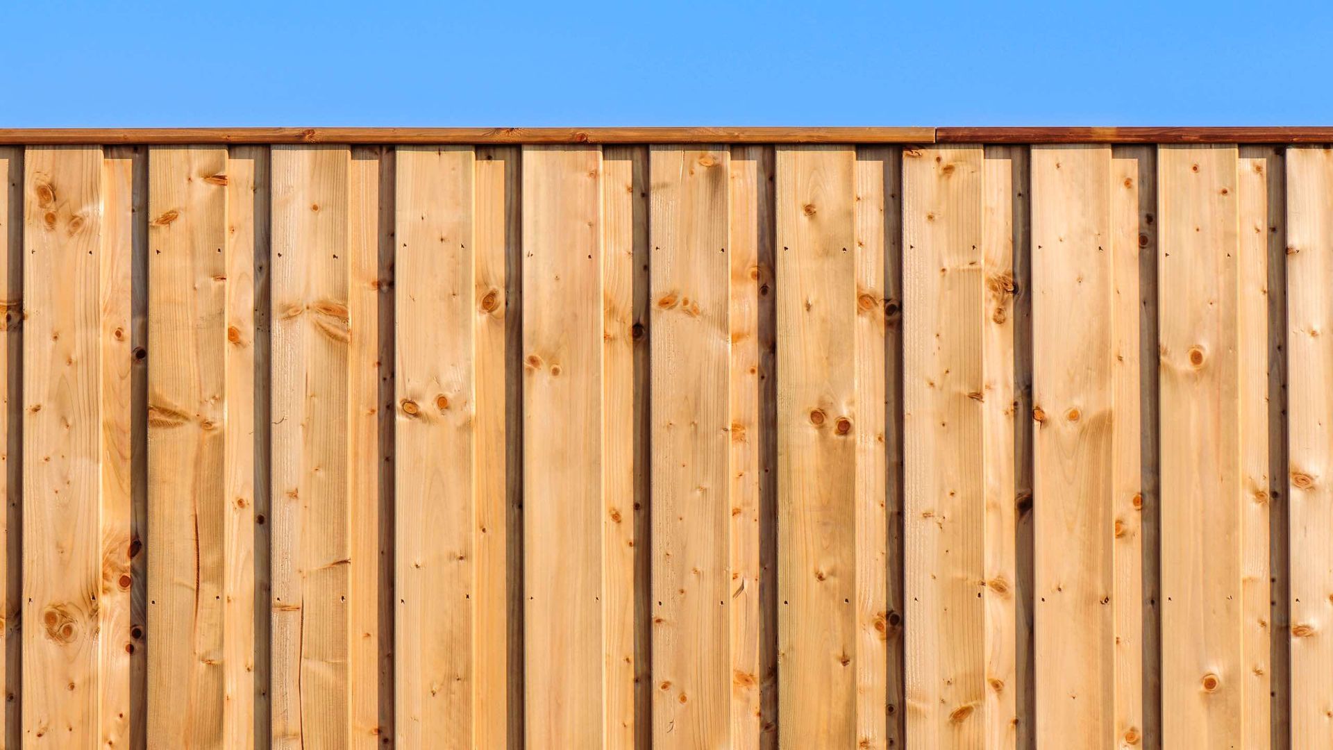 A wooden fence with a blue sky in the background.