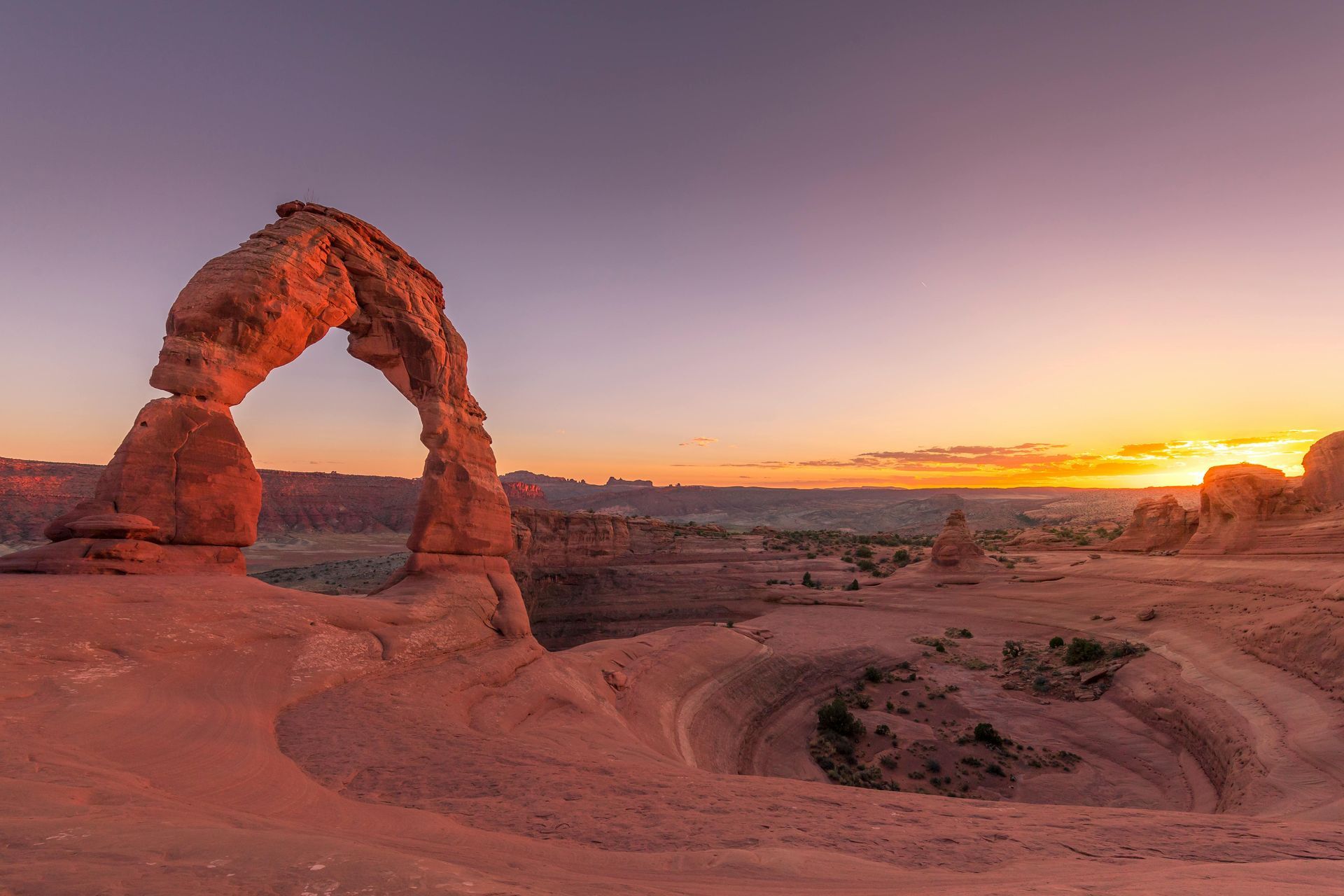 Delicate Arch at sunset over a red rock desert landscape in Utah