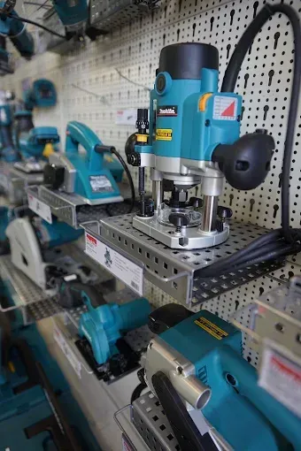 Présentation d'outils électriques, principalement des modèles Makita de couleur turquoise, sur une étagère de magasin.