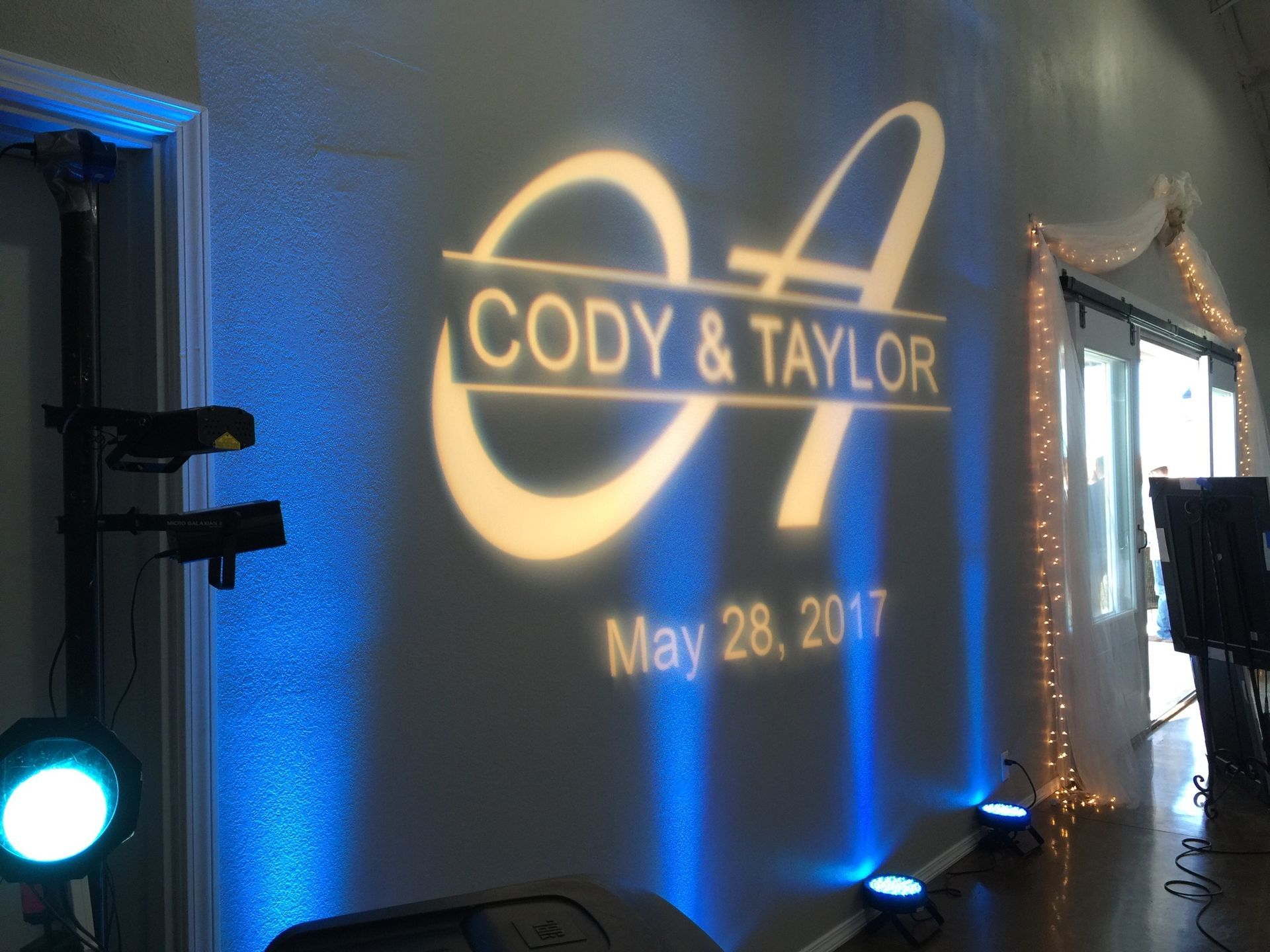 A wedding logo for cody and taylor is projected on a wall.