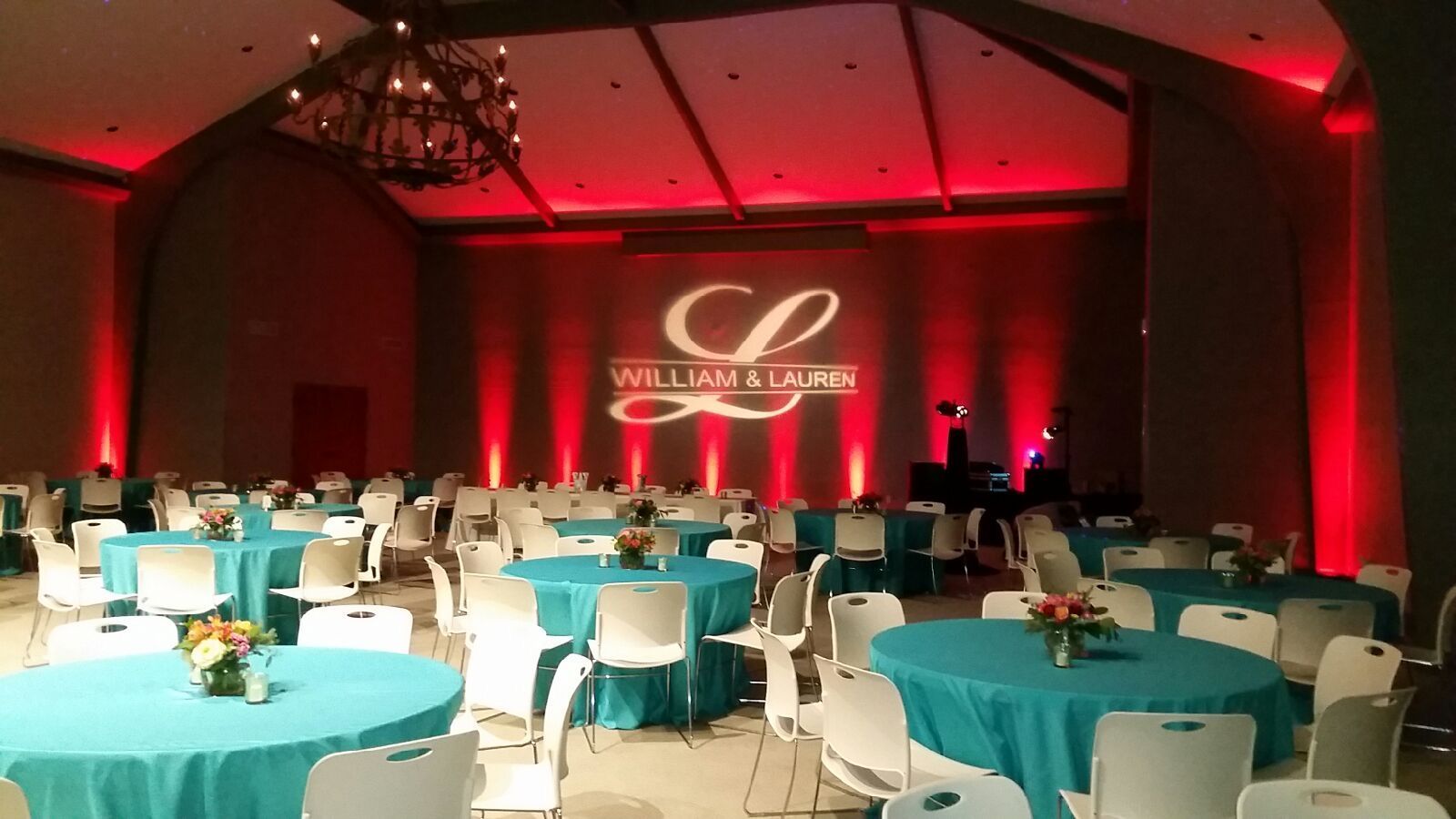 A large room with tables and chairs and a monogram on the wall