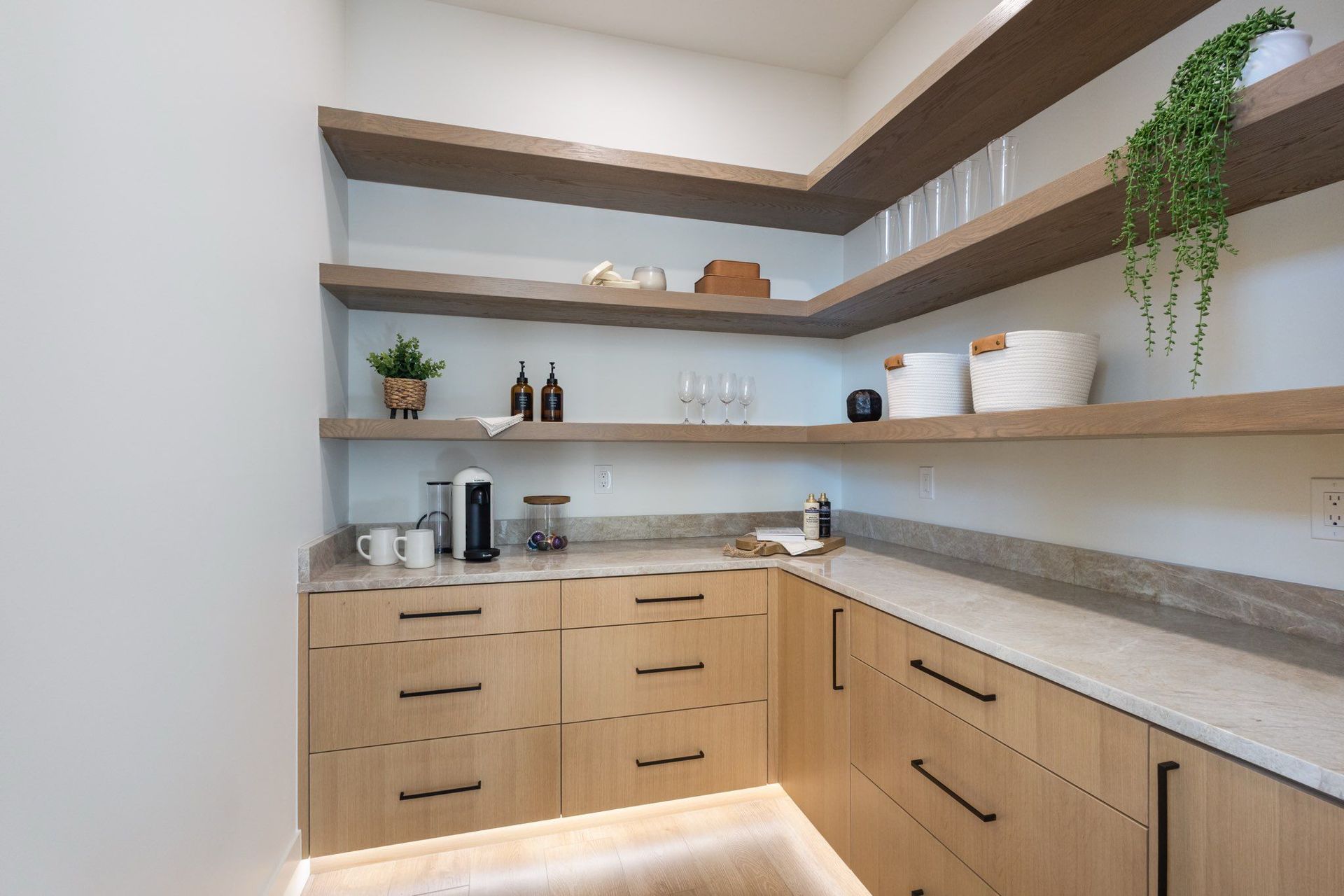 Pantry with wooden shelves and cabinets, a light countertop, and under-cabinet lighting.