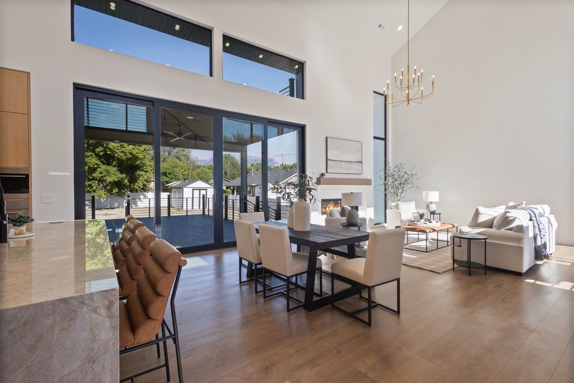 Open-concept dining/living area with large glass doors and high ceilings, wood floors, and modern furniture.