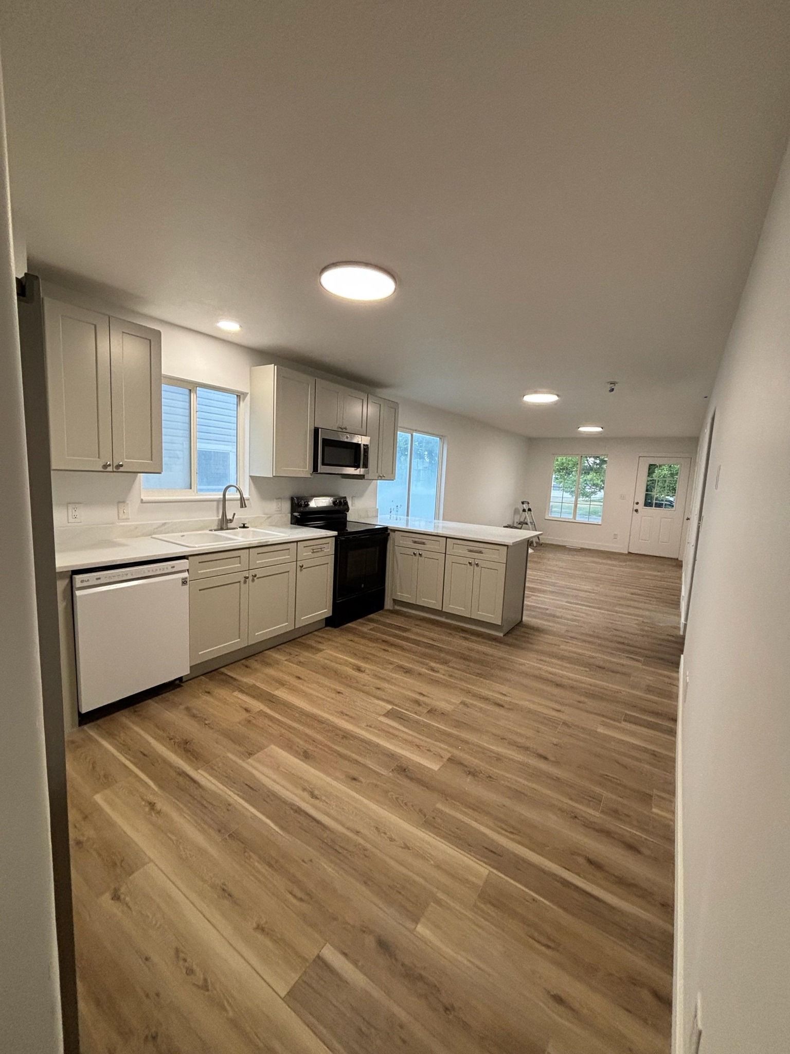 Kitchen with light gray cabinets, white countertops, and wood-look flooring.