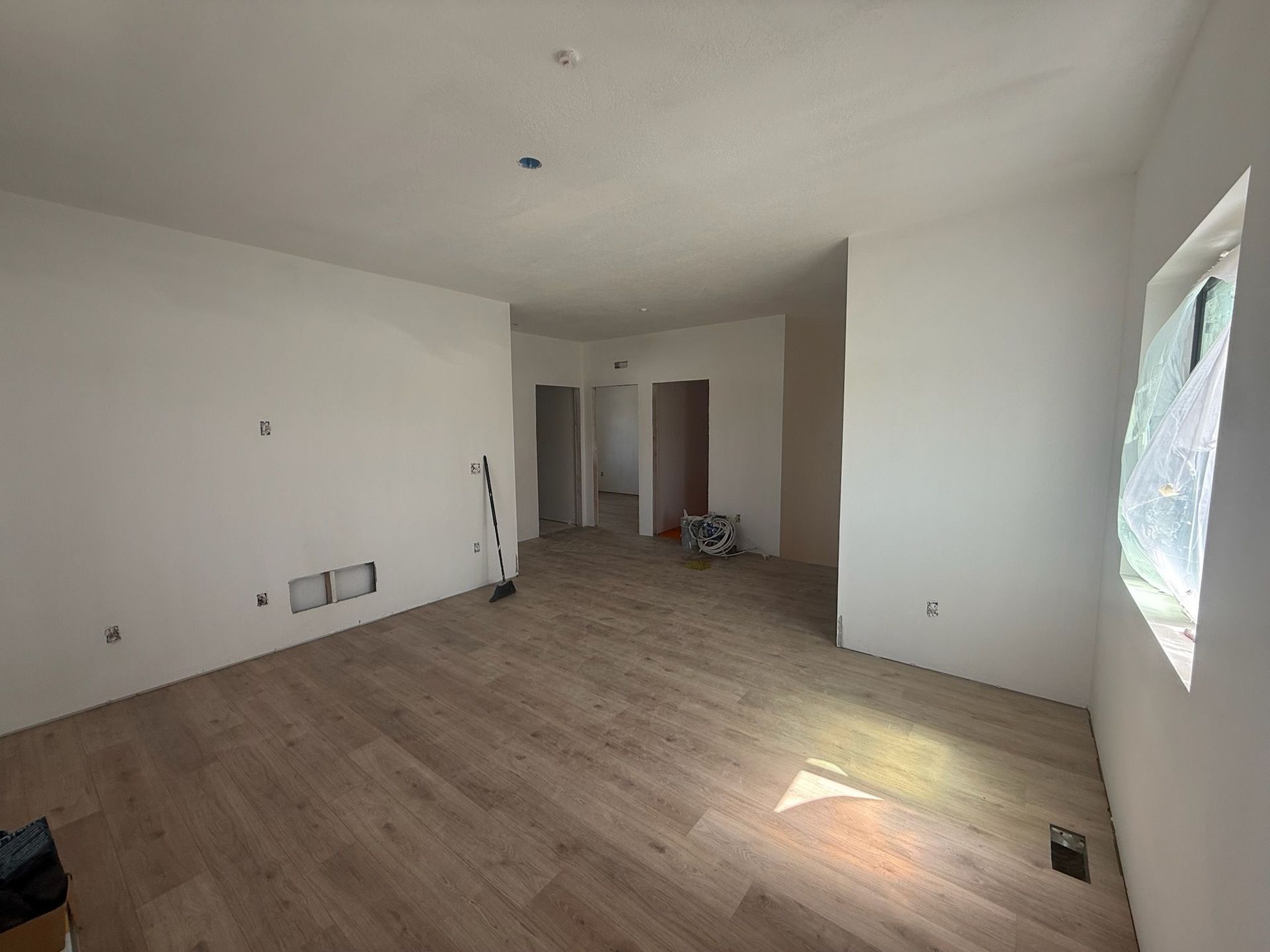 Empty room with wood floors, white walls, and a window.