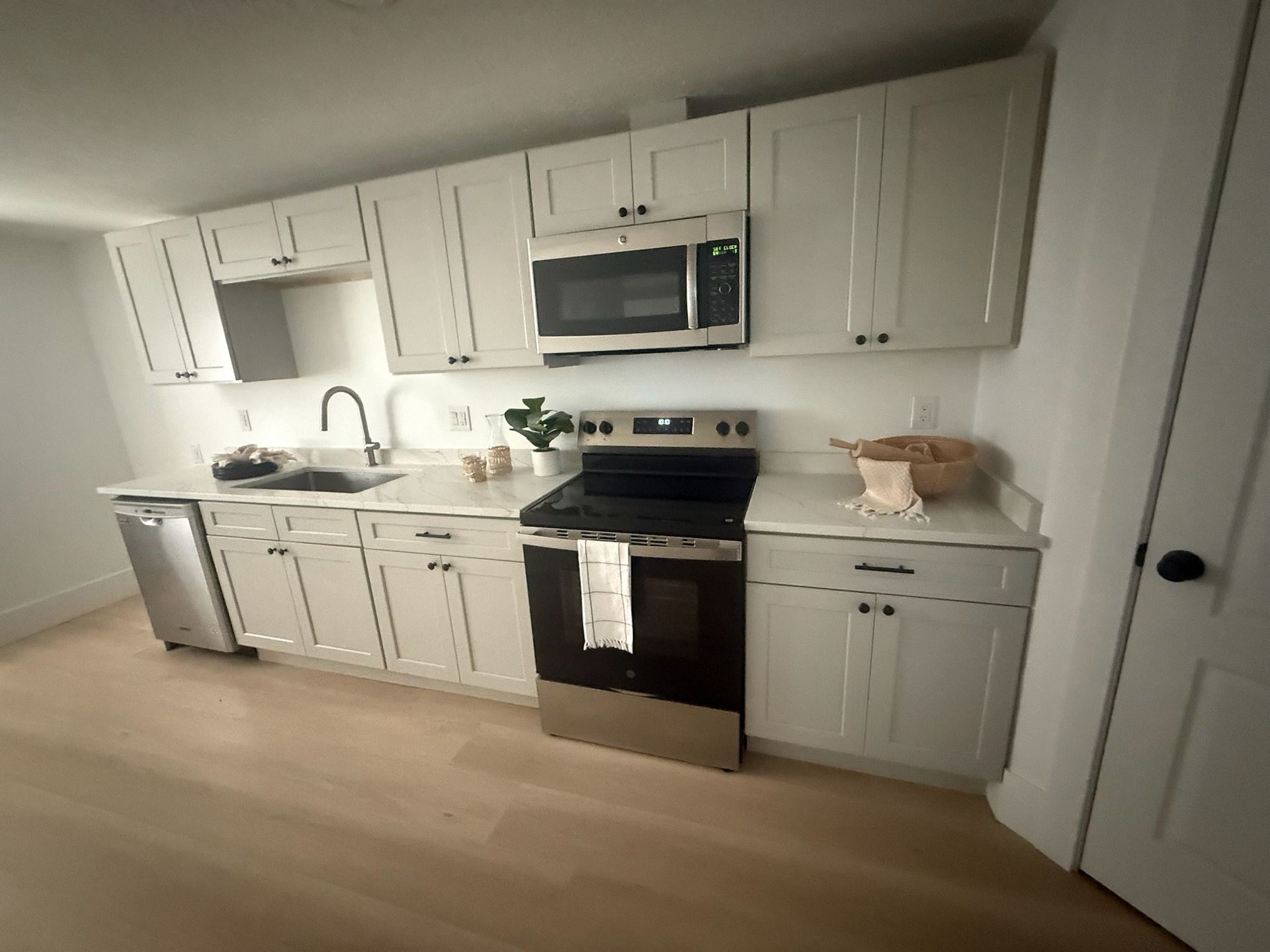 White kitchen with cabinets, appliances, and countertops; a stainless steel oven and dishwasher.