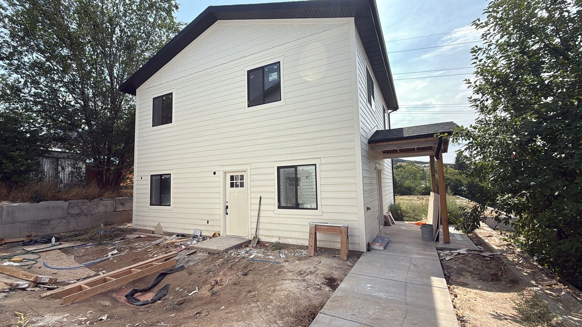 Two-story house with white siding and a small porch; construction site in front.
