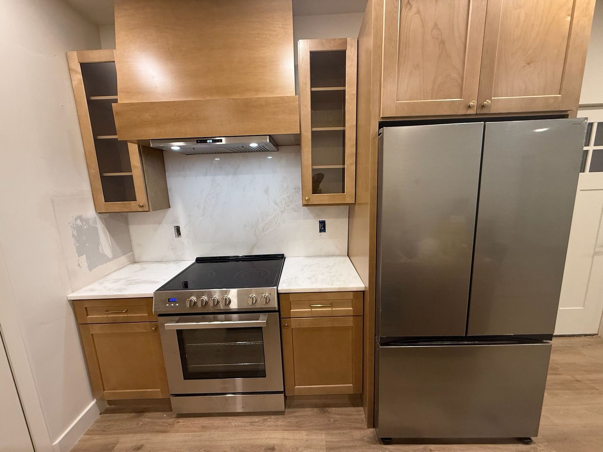 Kitchen with light wood cabinets, stainless steel appliances, and white countertops.