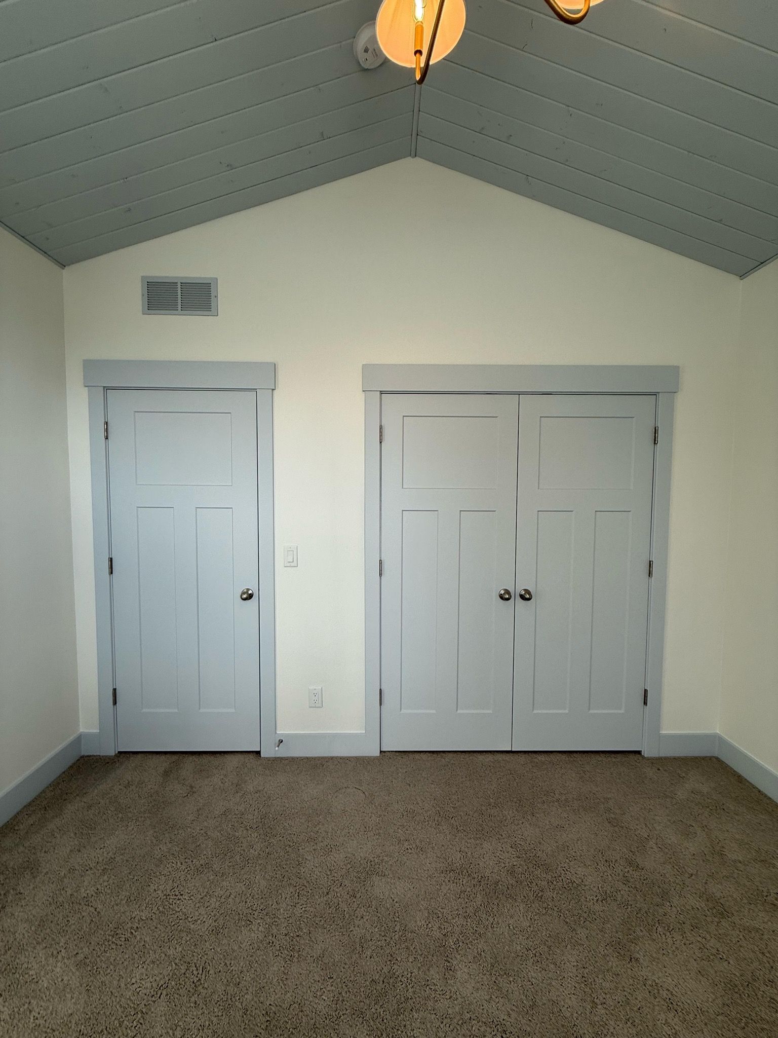Light blue doors and trim on white walls in a room with a patterned carpet and a high ceiling.
