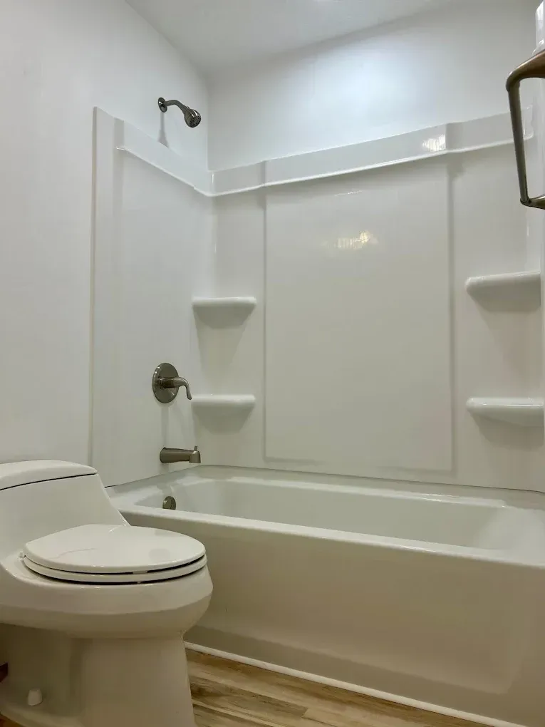 White bathroom with a tub, shower, and toilet.