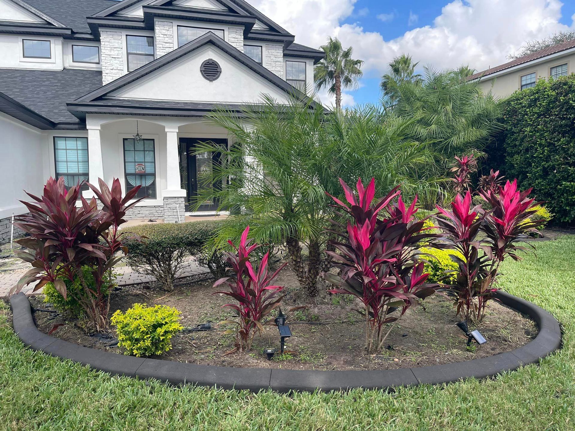 A large white house with a lush green lawn and a garden in front of it.