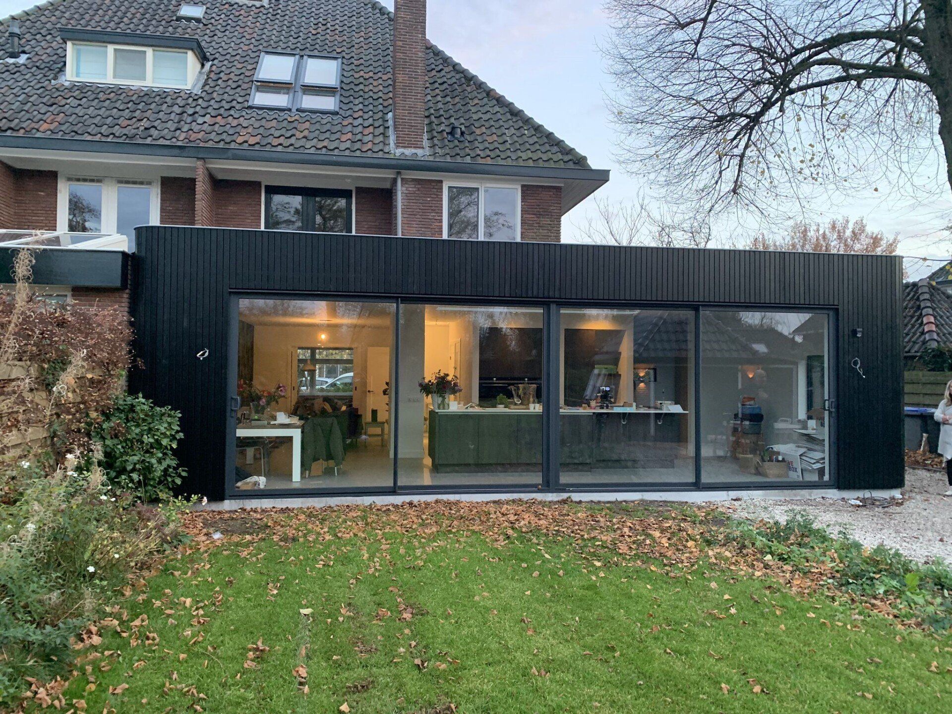 Een groot huis met veel ramen en een zwart dak.