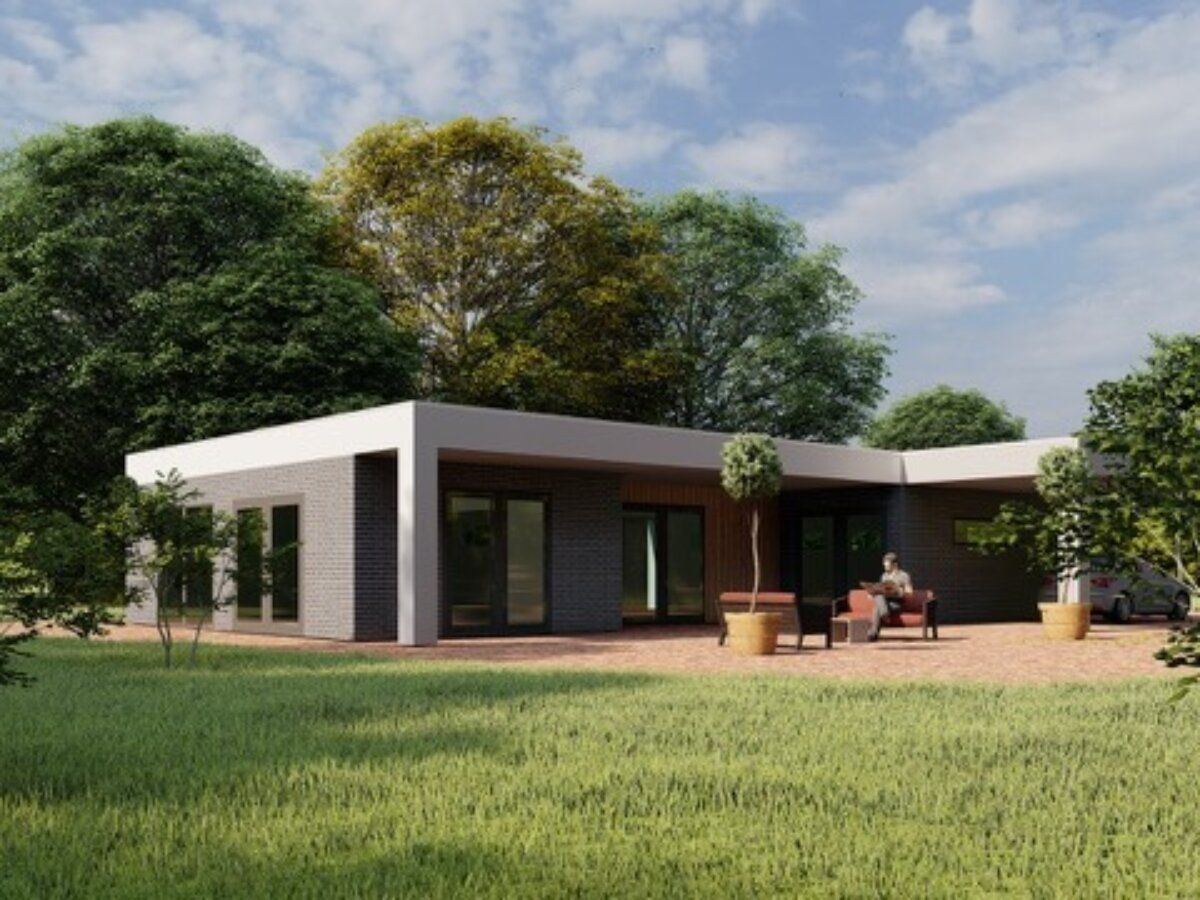 Een man zit op een bankje voor een huis omgeven door bomen