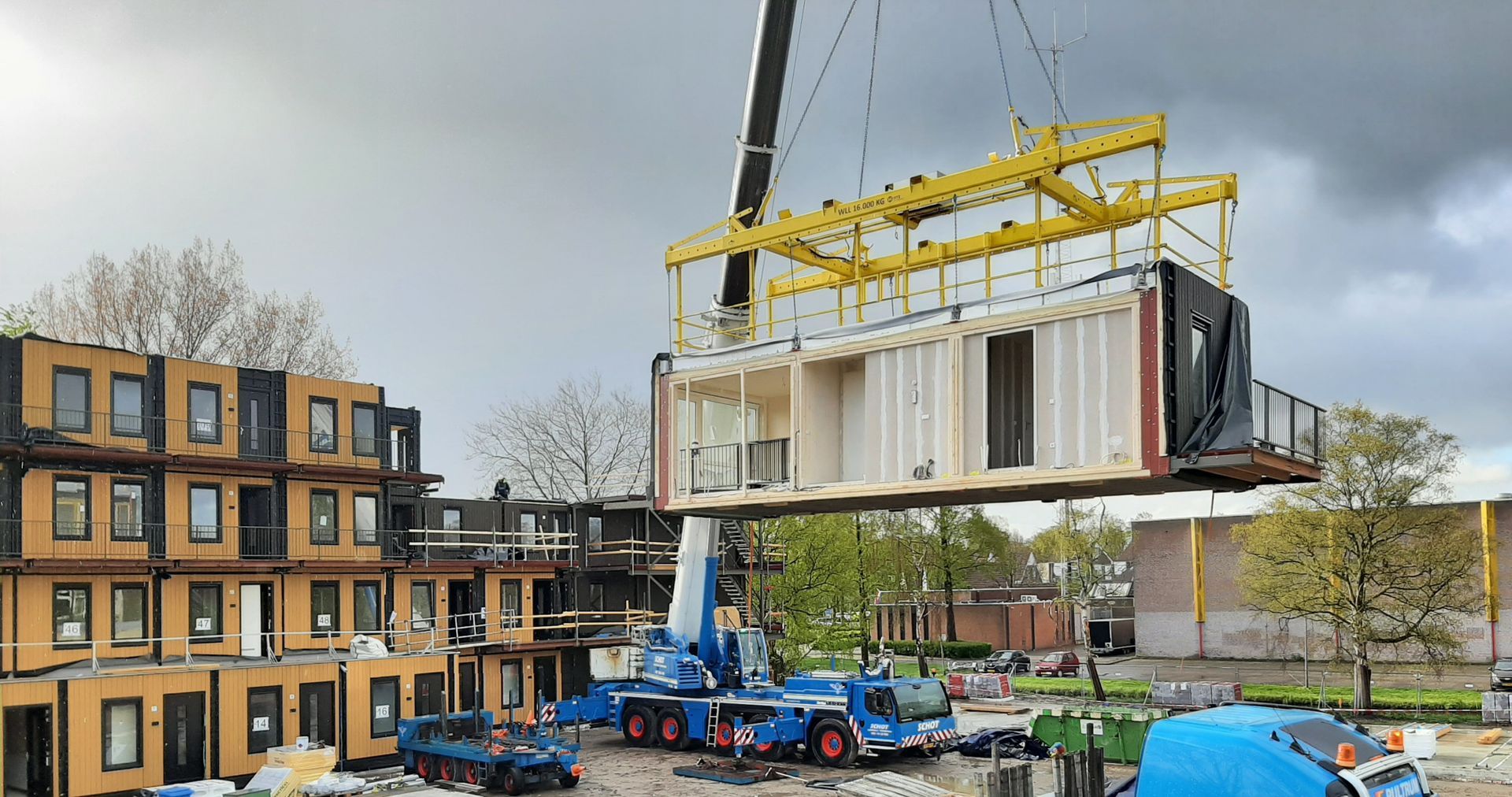 Een kraan tilt een groot stuk hout in de lucht.