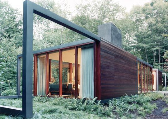 Een modern huis met veel ramen is omgeven door bomen.