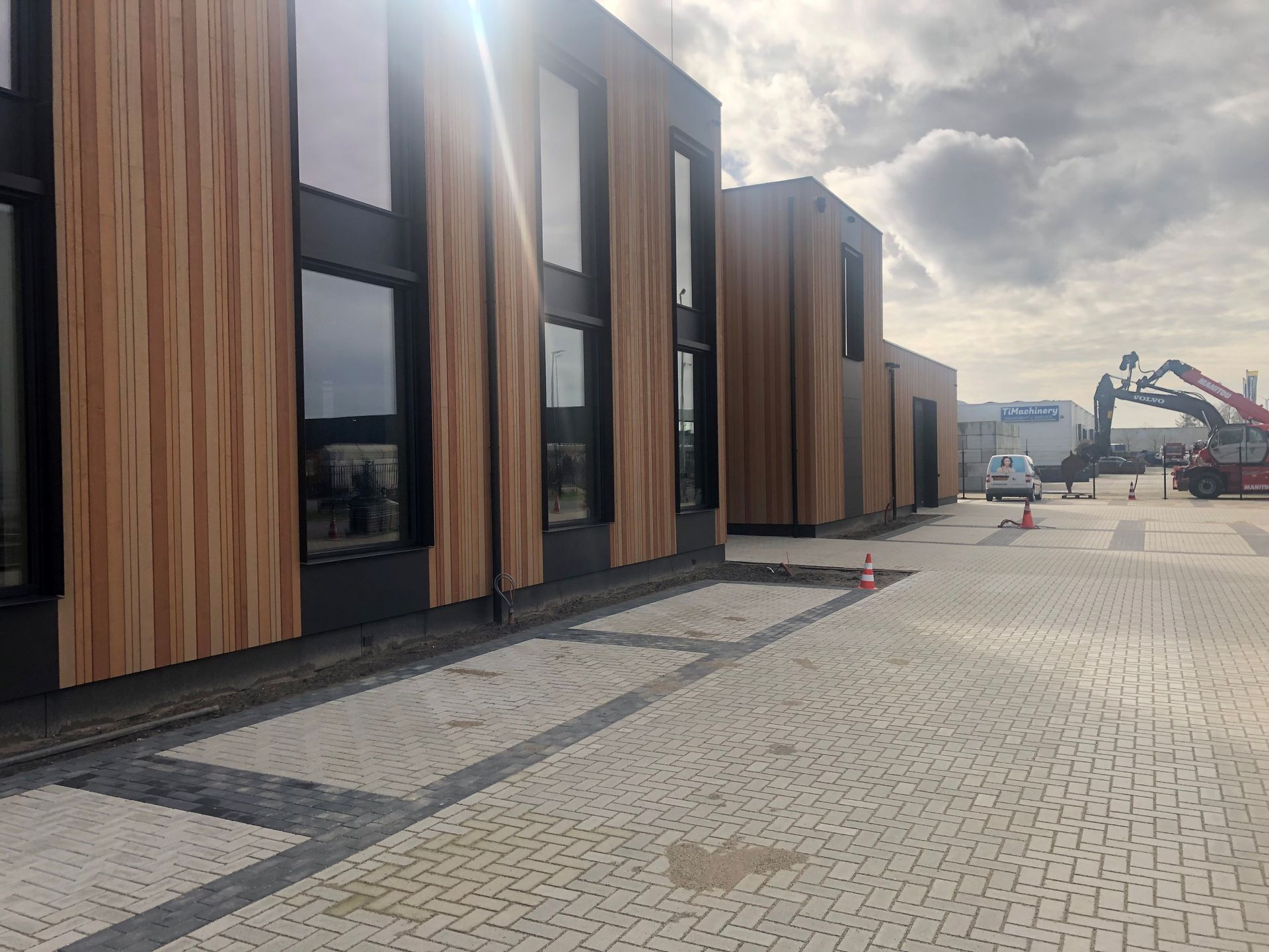 Een gebouw met veel ramen en een oprit van baksteen ervoor.