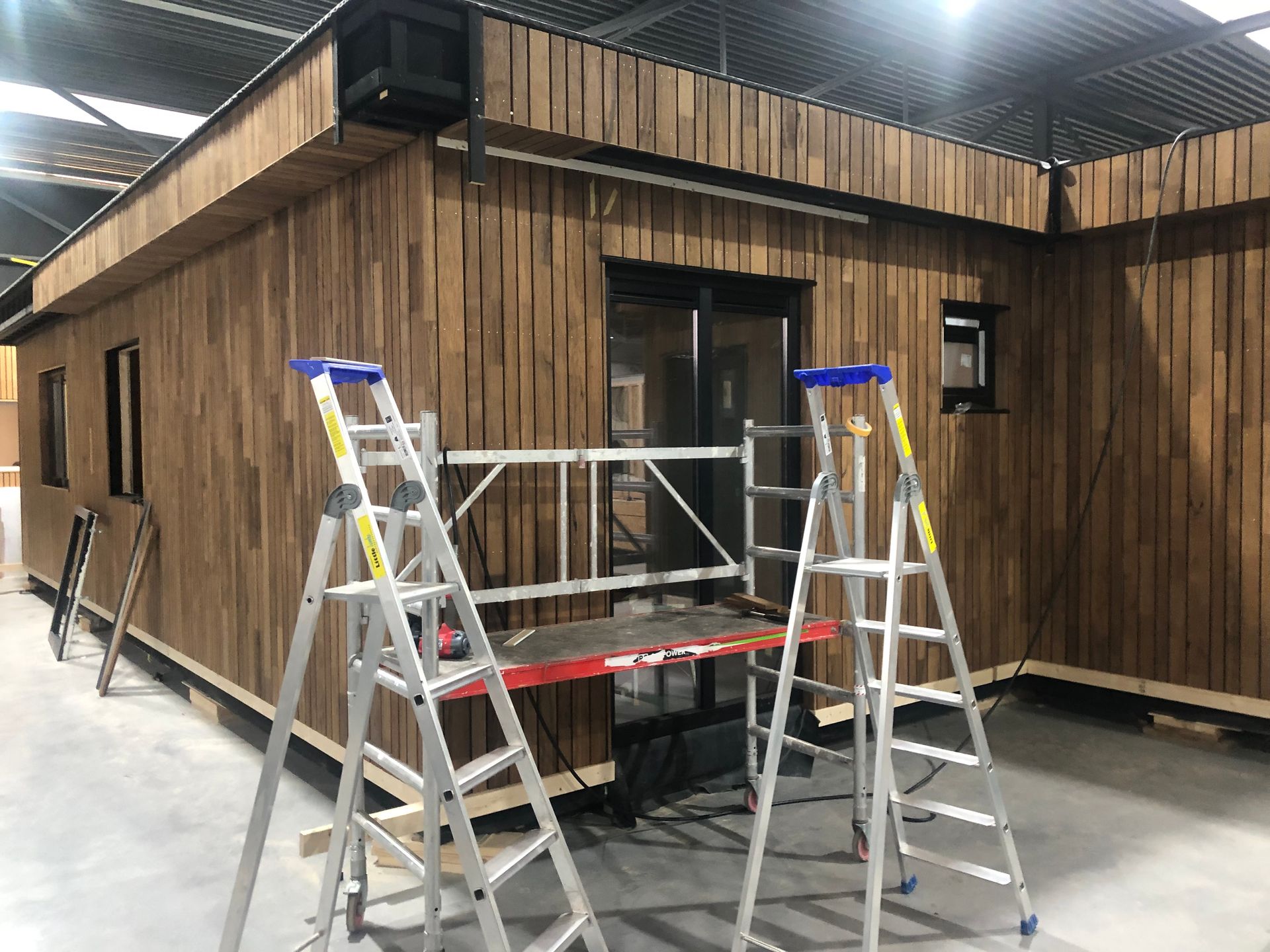 Twee ladders staan ​​voor een houten gebouw.