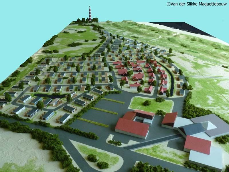 Een model van een woonwijk met een vuurtoren op de achtergrond