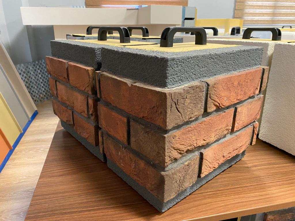 Een bakstenen blok ligt op een houten tafel.